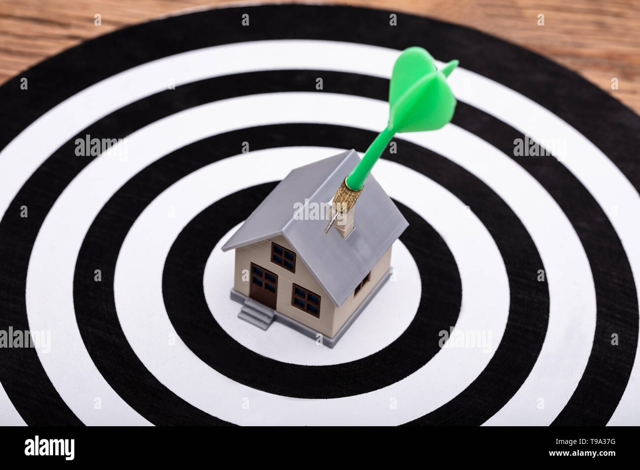 Close-up Of Green Dart Arrow Hitting House Model On Dartboard Stock Photo