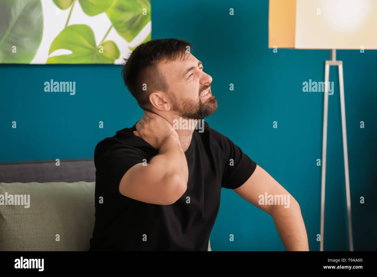 Man suffering from neck pain at home Stock Photo - Alamy