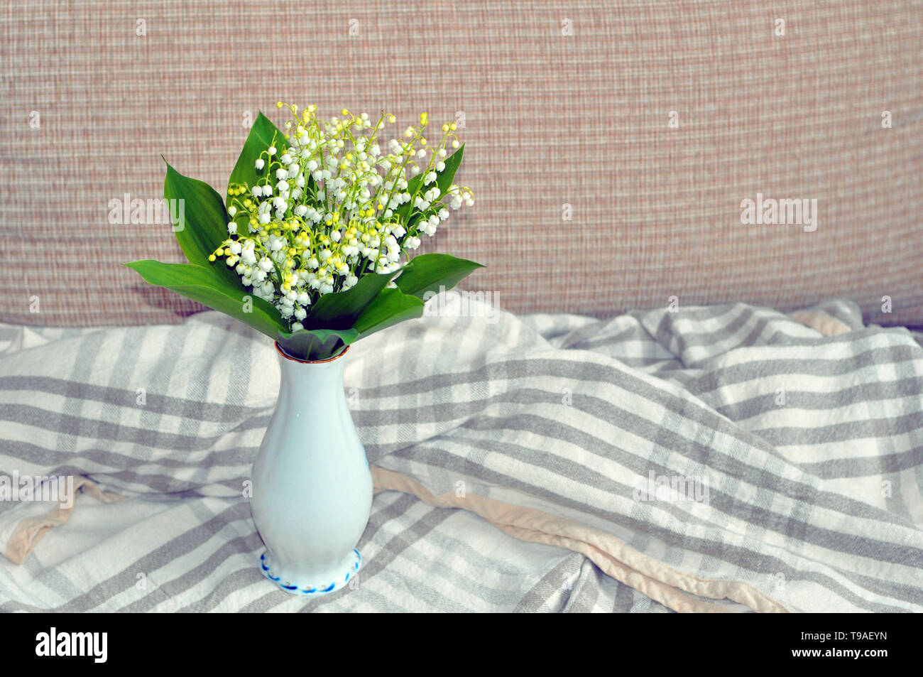 Still life with a bouquet of white lilies of the valley in a beautiful ...