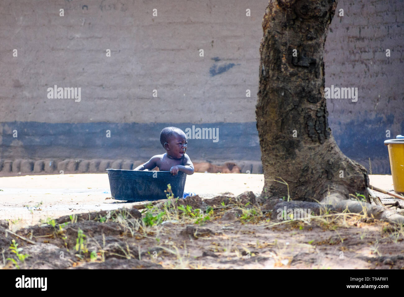 Malawian baby sitting in a plastic bowl is crying for attention Stock Photo