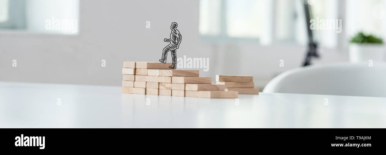 Wide view image of hand drawn silhouette of a businessman climbing up the steps made of wooden pegs on a business office desk. Stock Photo