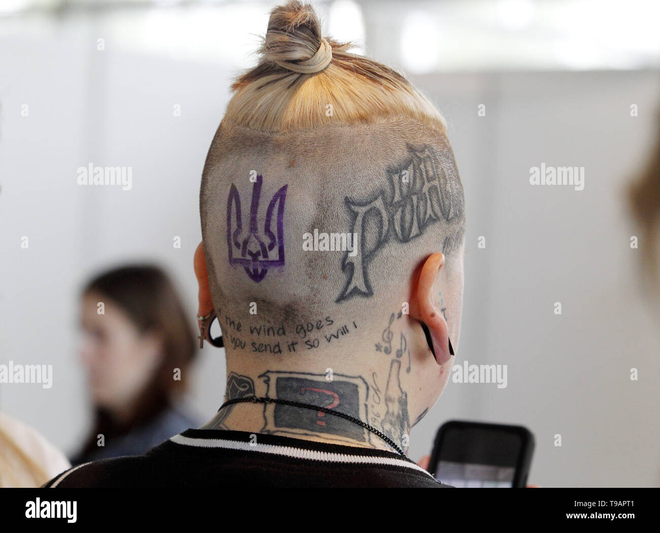Kiev, Ukraine. 17th May, 2019. A girl with a sketch of the tattoo in the  form of the Ukrainian coat of arms on her nape attends the annual  International 'Tattoo Collection 2019''