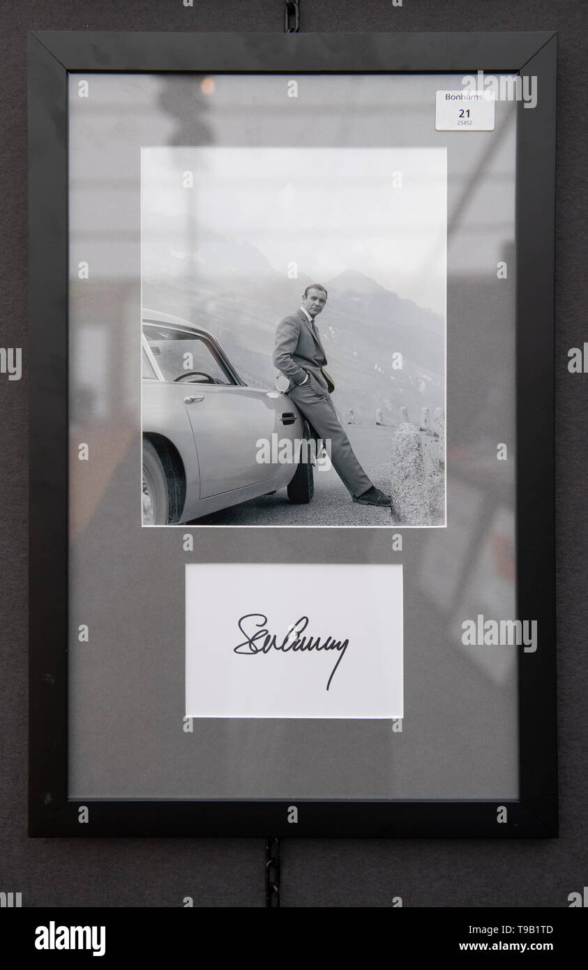 The Wormsley Estate, Stokenchurch, UK. 18th May 2019. 20th Anniversary edition of Bonhams annual sale dedicated to Aston Martin and Lagonda takes place on 19th May 2019. Image: Autographed photograph of Sean Connery as James Bond with the ‘Goldfinger’ Aston Martin DB5, estimate £250-350. Credit: Malcolm Park/Alamy Live News. Stock Photo