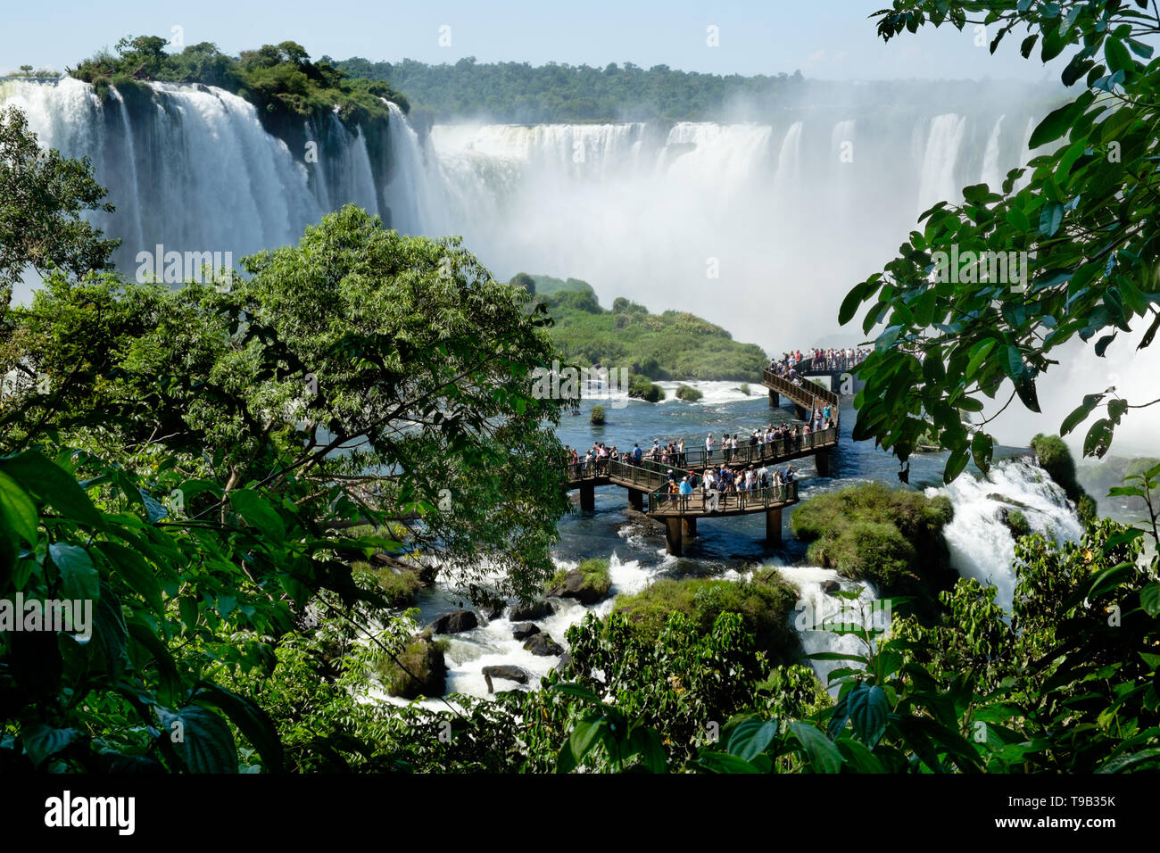 People stood along the raised walkway leading out into the middle of Iguacu Falls on the Brazilian side Stock Photo