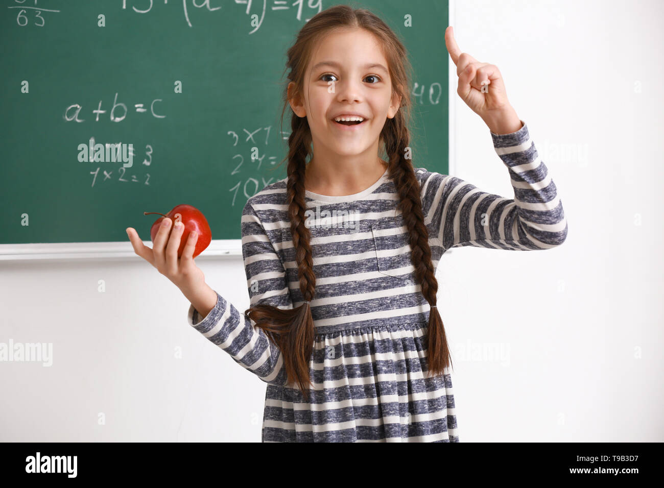 Cute girl with raised index finger in classroom Stock Photo