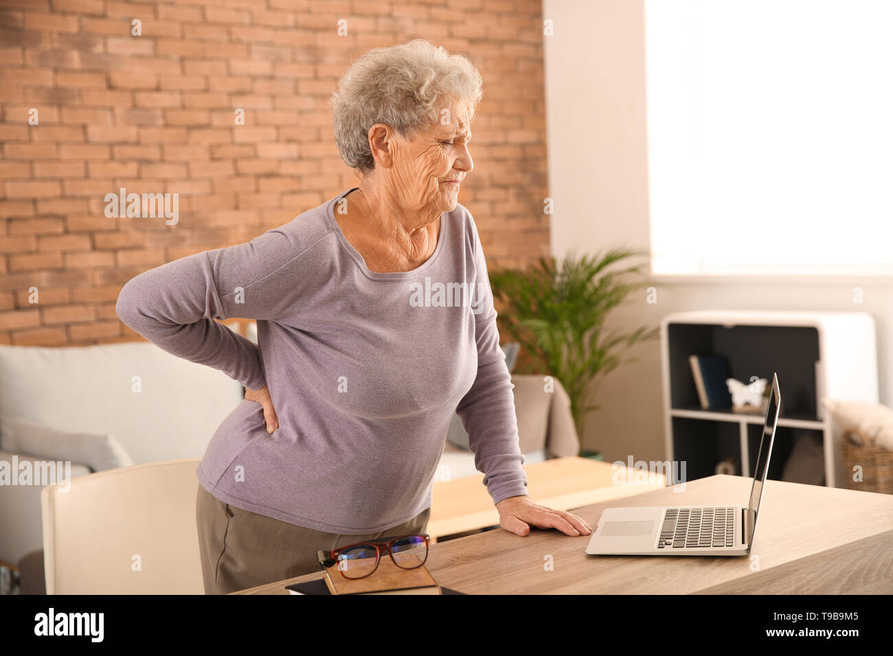Senior woman suffering from back pain at home Stock Photo - Alamy