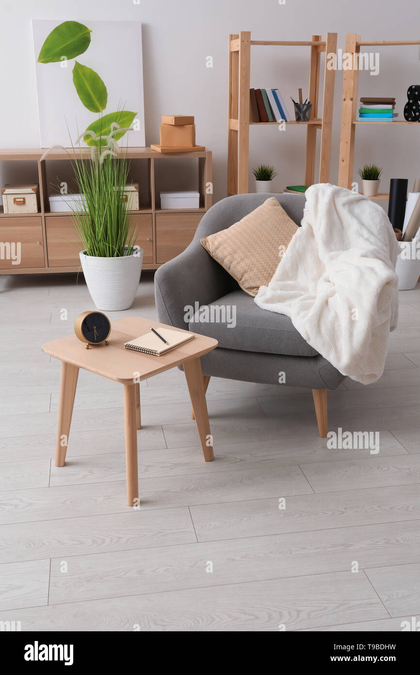 Interior of light room with cozy armchair and table Stock Photo - Alamy