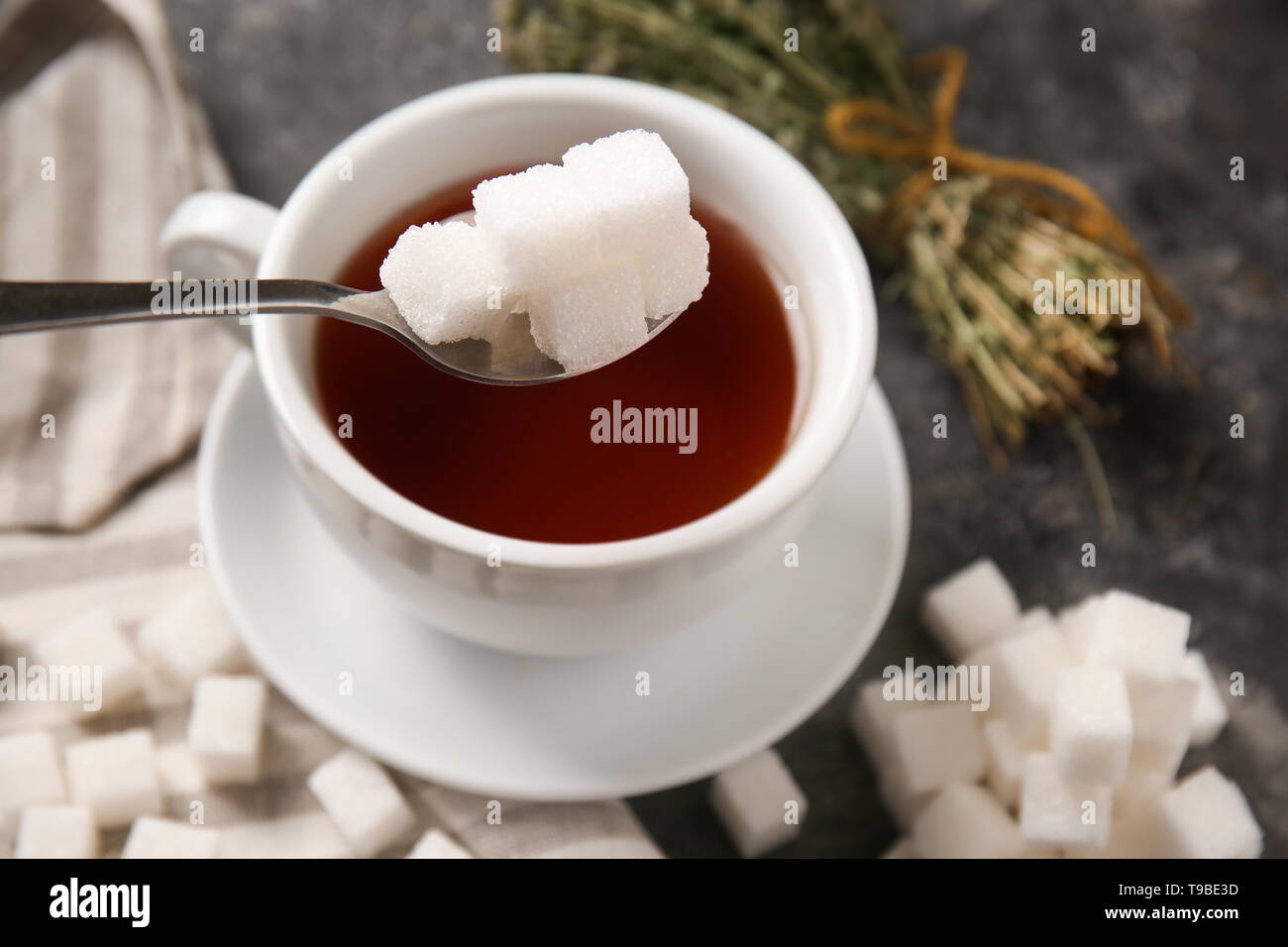Adding of sugar to cup with aromatic tea on grey table Stock Photo - Alamy