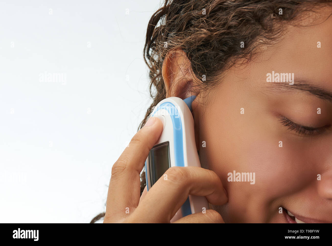 Woman using digital thermometer isolated.  Ear side on white background Stock Photo