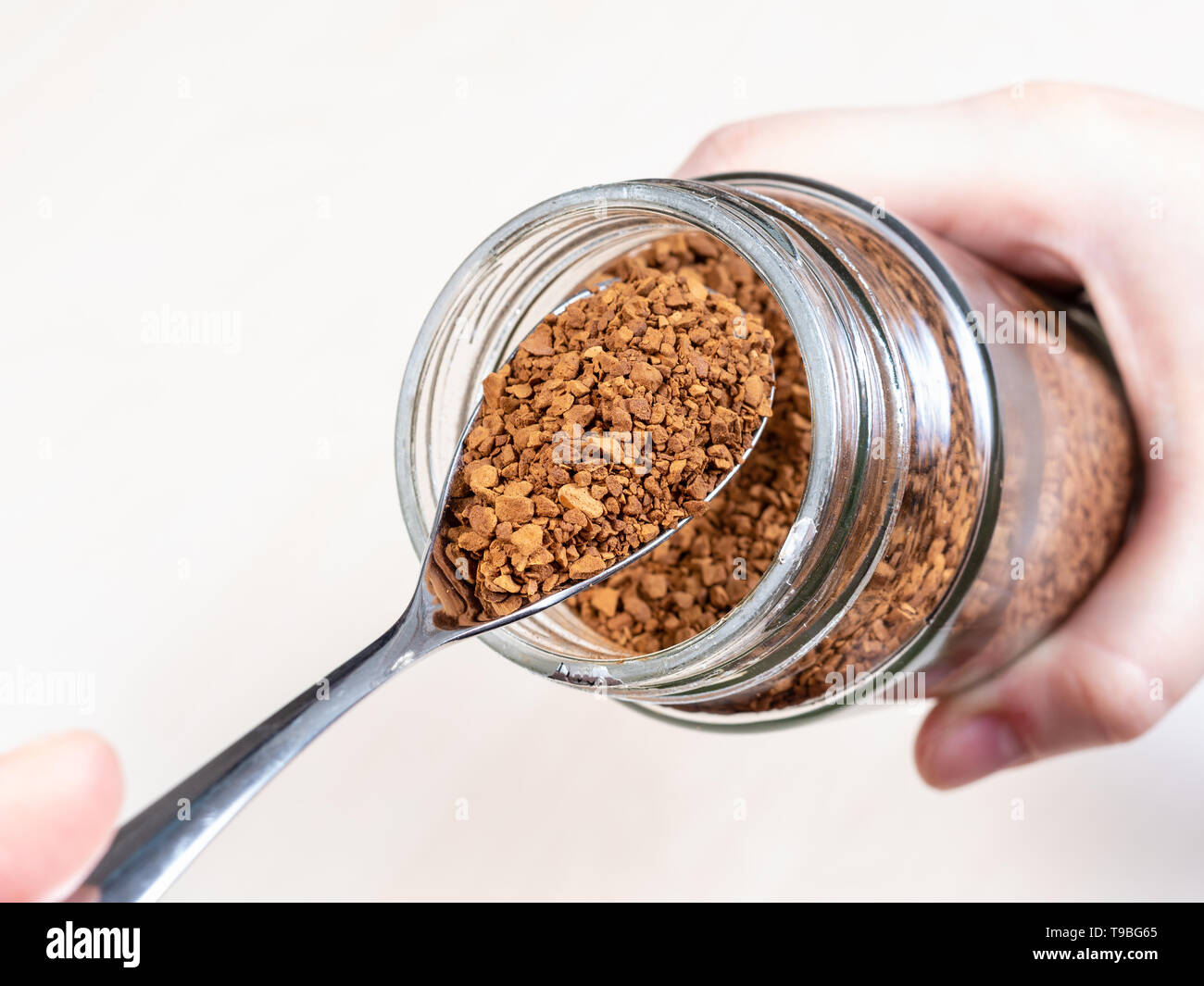 spoon with portion of instant coffee over glass jar close up Stock Photo