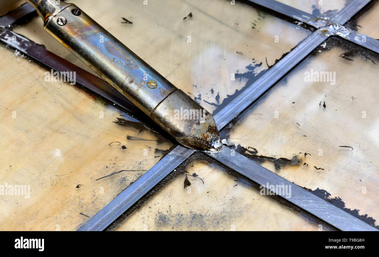 Soldering lead came in a leaded glass window pain with electric soldering iron Stock Photo