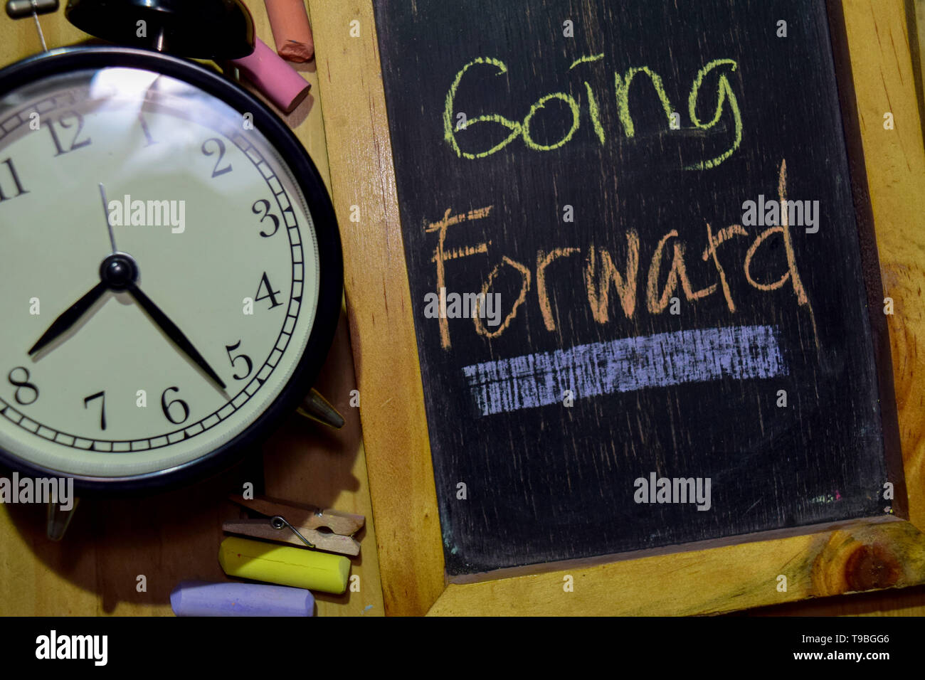 Going Forward on phrase colorful handwritten on chalkboard and alarm ...