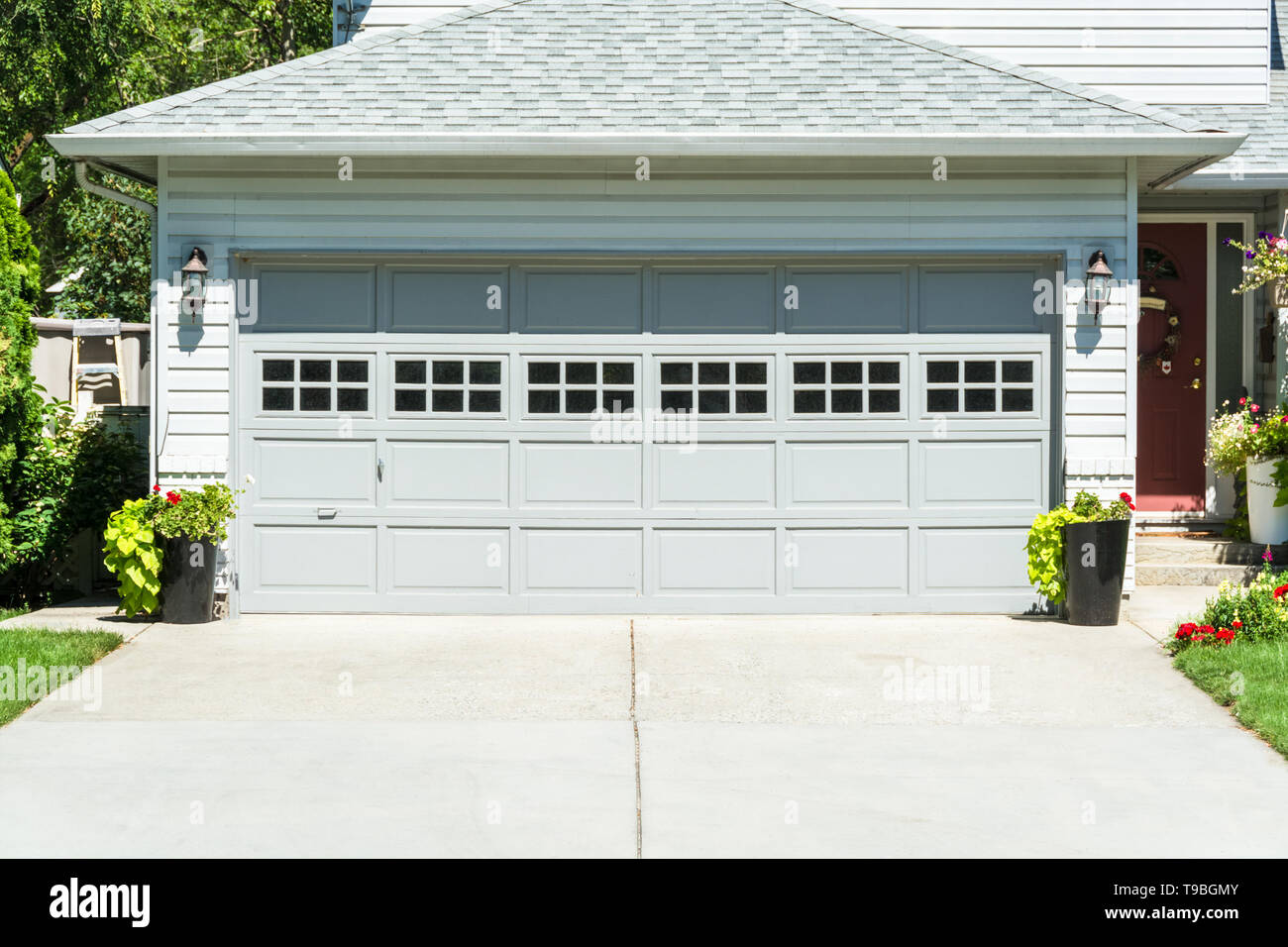 Wide Garage Door Of Residential House And Concrete Driveway In