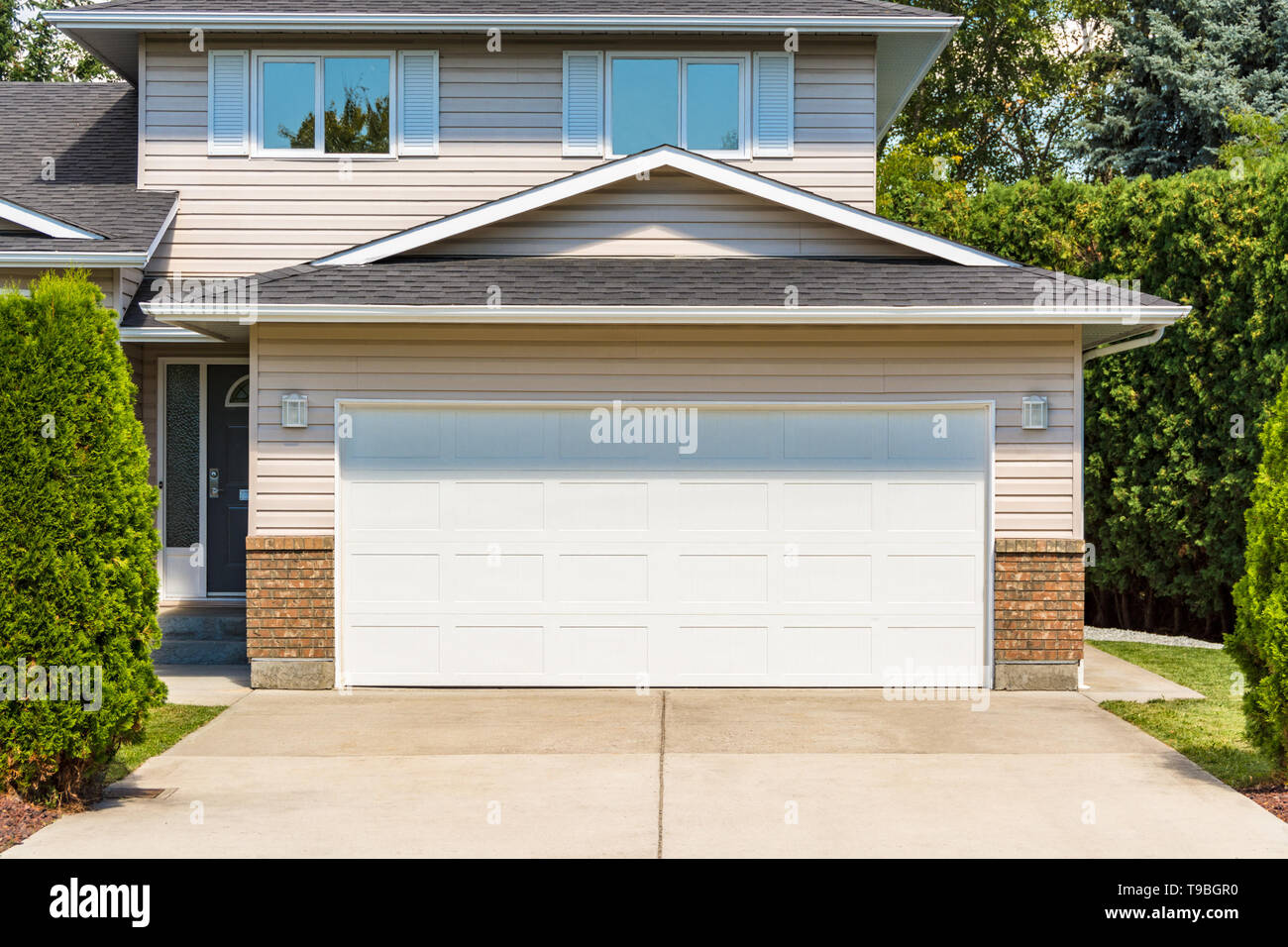 White Wide Garage Door Of Residential House With Concrete Driveway