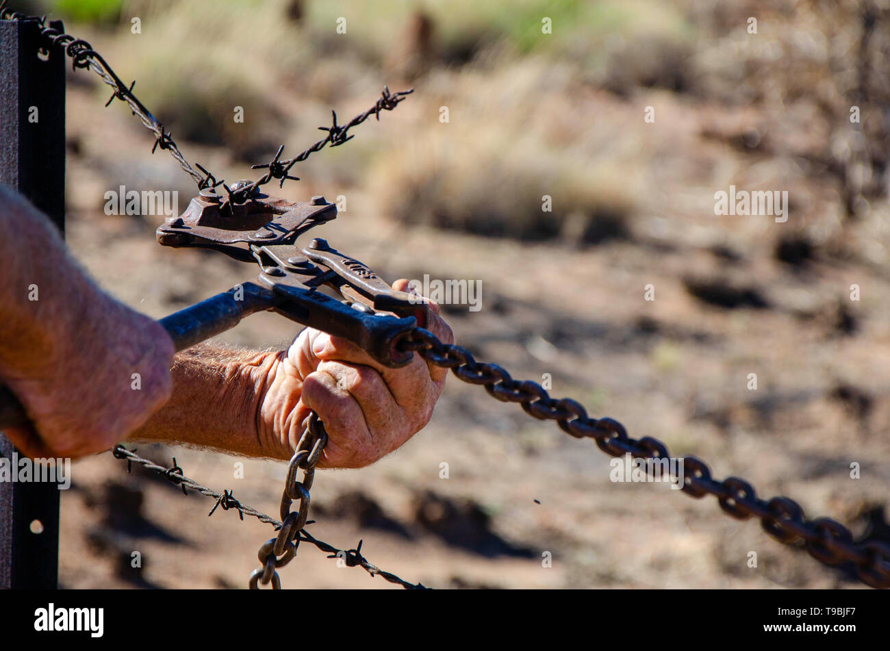 A man repairs a barb wire fence in Outback Australia using fencing