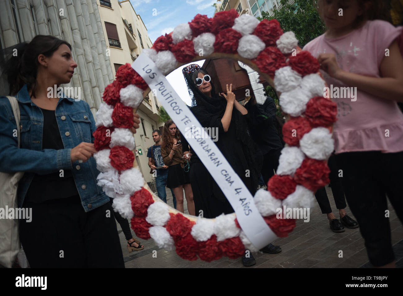 Demonstrators seen carrying flowers during the protest. The association of down town neighbours from Malaga have organized a symbolic funeral of a neighbour as part of a performance against the high cost of housing and rent because of property speculation in Malaga centre. Stock Photo