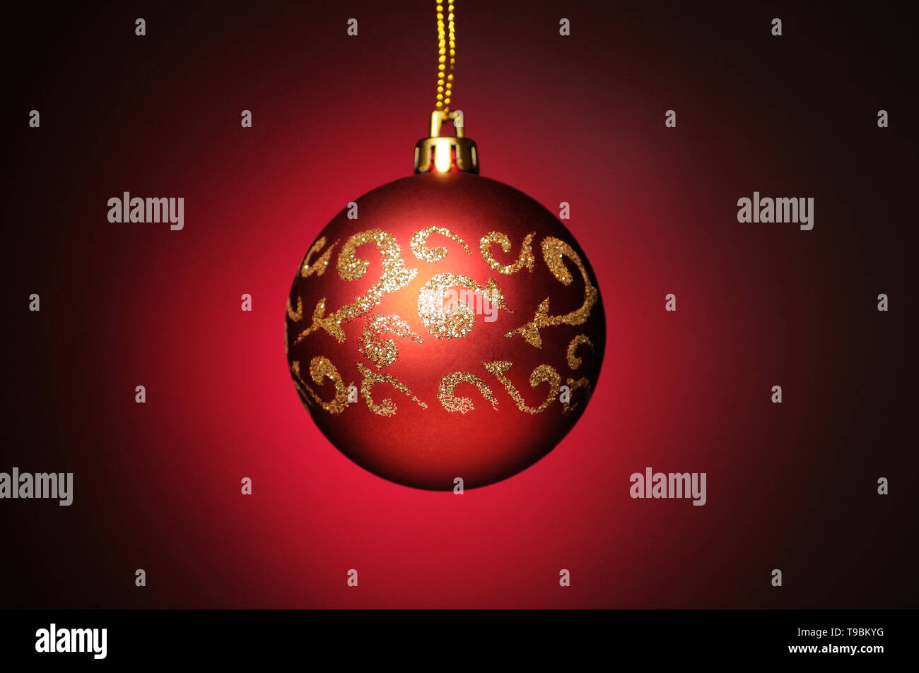 Red Christmas bauble hanging on a gold string Stock Photo - Alamy