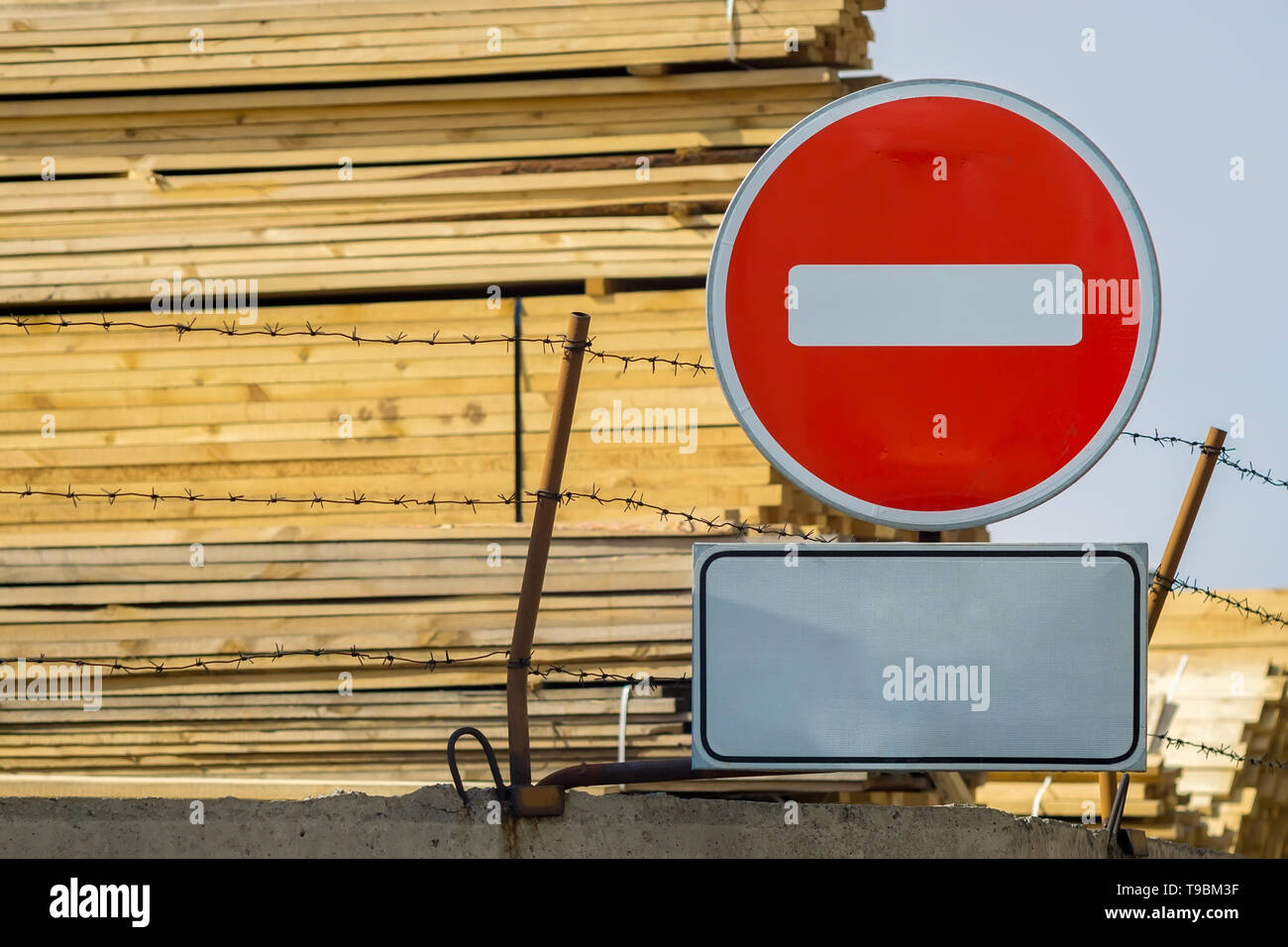 sign, symbol, warning about the prohibition of entry to the territory of the industrial zone with building materials, lumber, placed on the fence Stock Photo