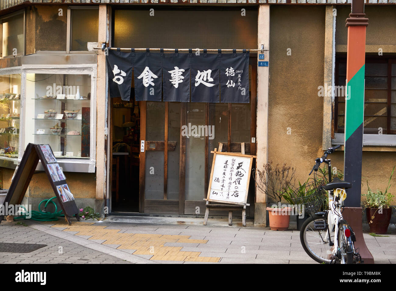 A tempura restaurant named Tokusen (徳仙) on a corner in Rokku Dori Street in Asakusa, Tokyo. Sample food in the window and noren curtain over the door. Stock Photo