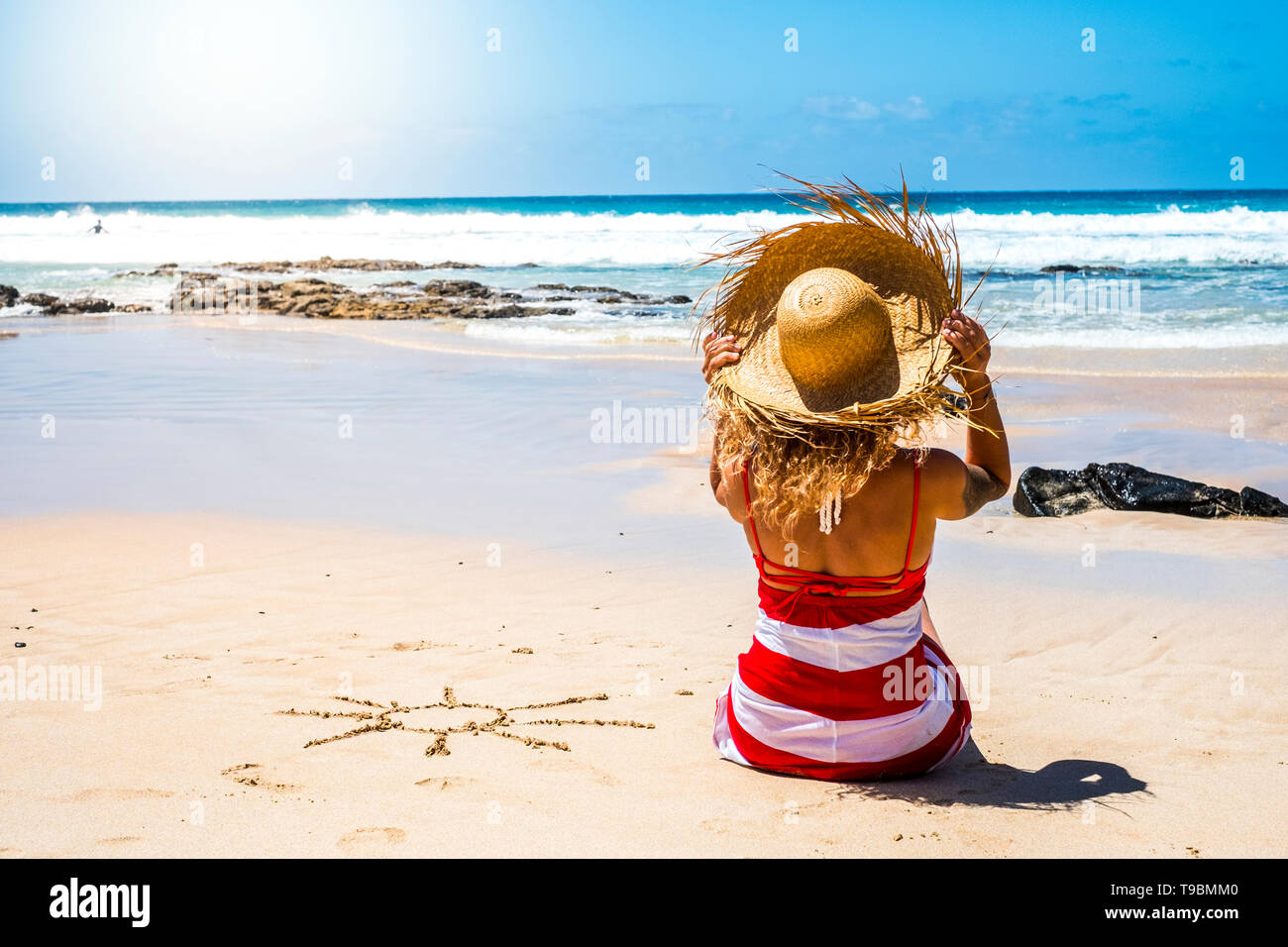 Summer holiday vacation at the beach in paradise beautiful resort people concept with nice woman with tourist hat viewed from back enjoying the sand a Stock Photo