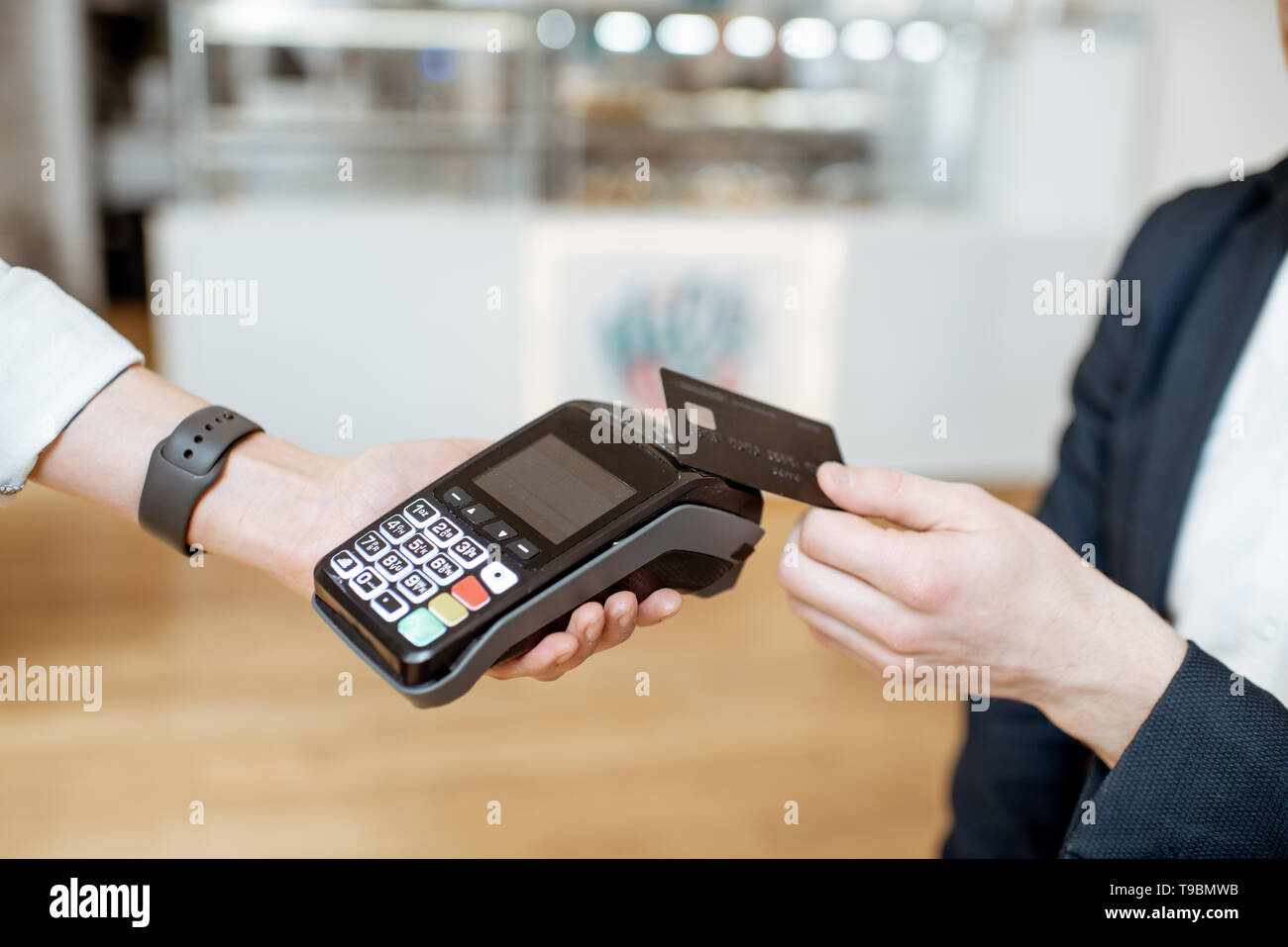 Businessman paying contactless with bank card at the cafe, close-up view Stock Photo