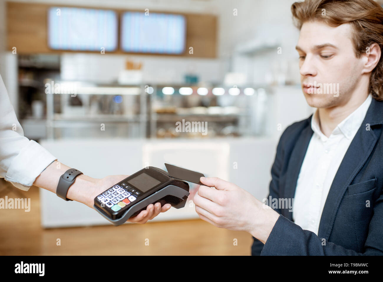 Businessman paying contactless with bank card at the cafe Stock Photo