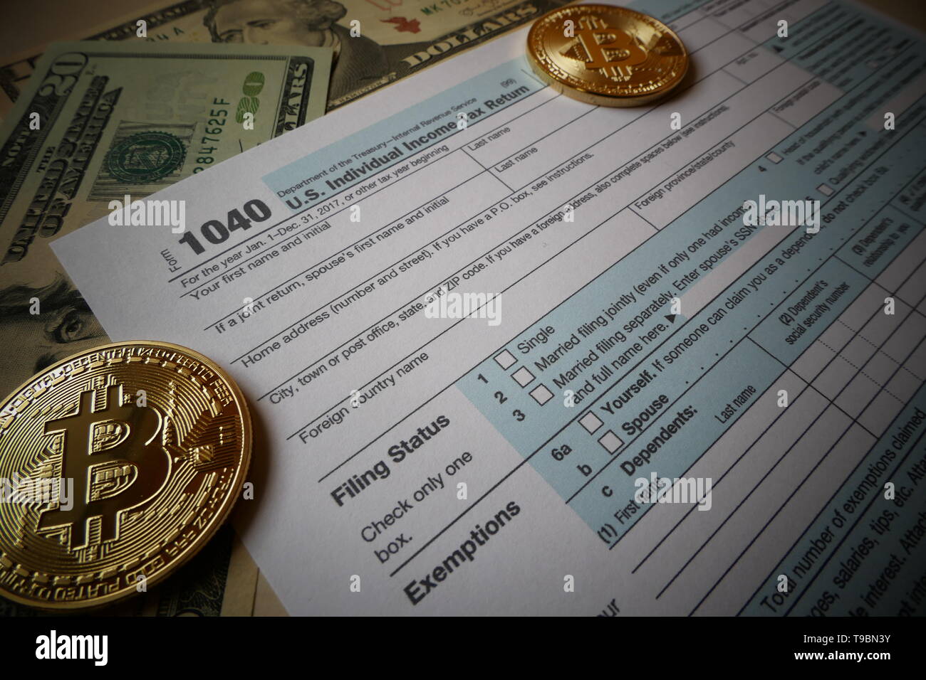 Two golden Bitcoins, an virtual currency in physical coin form, displayed with the US 1040 Tax form, symbolic illustration for the taxation of bitcoin Stock Photo