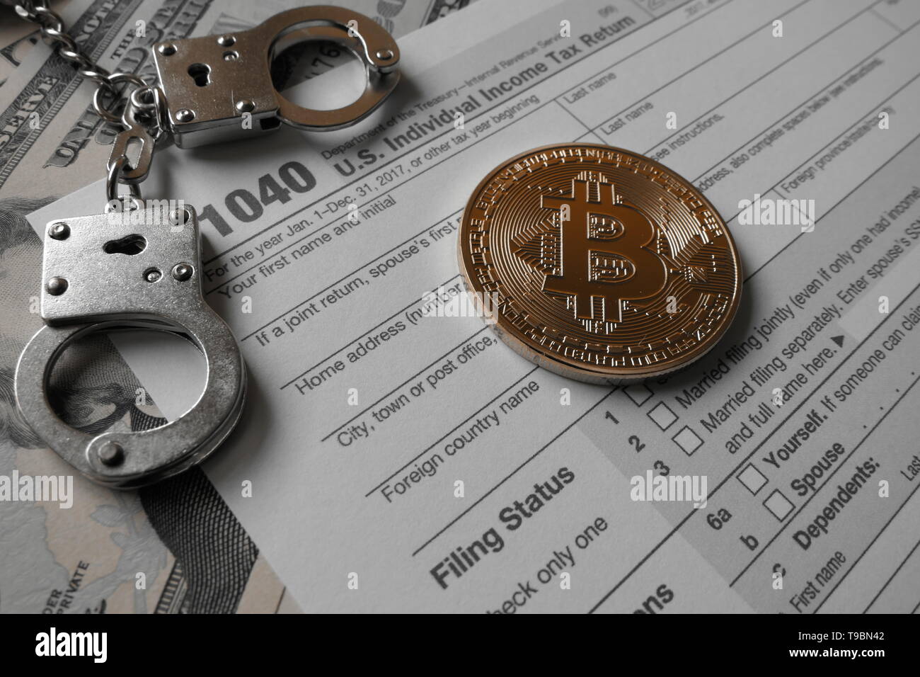 An golden Bitcoin, an virtual currency in physical coin form, displayed with handcuffs and the US 1040 Tax form, symbolic illustration for the taxatio Stock Photo