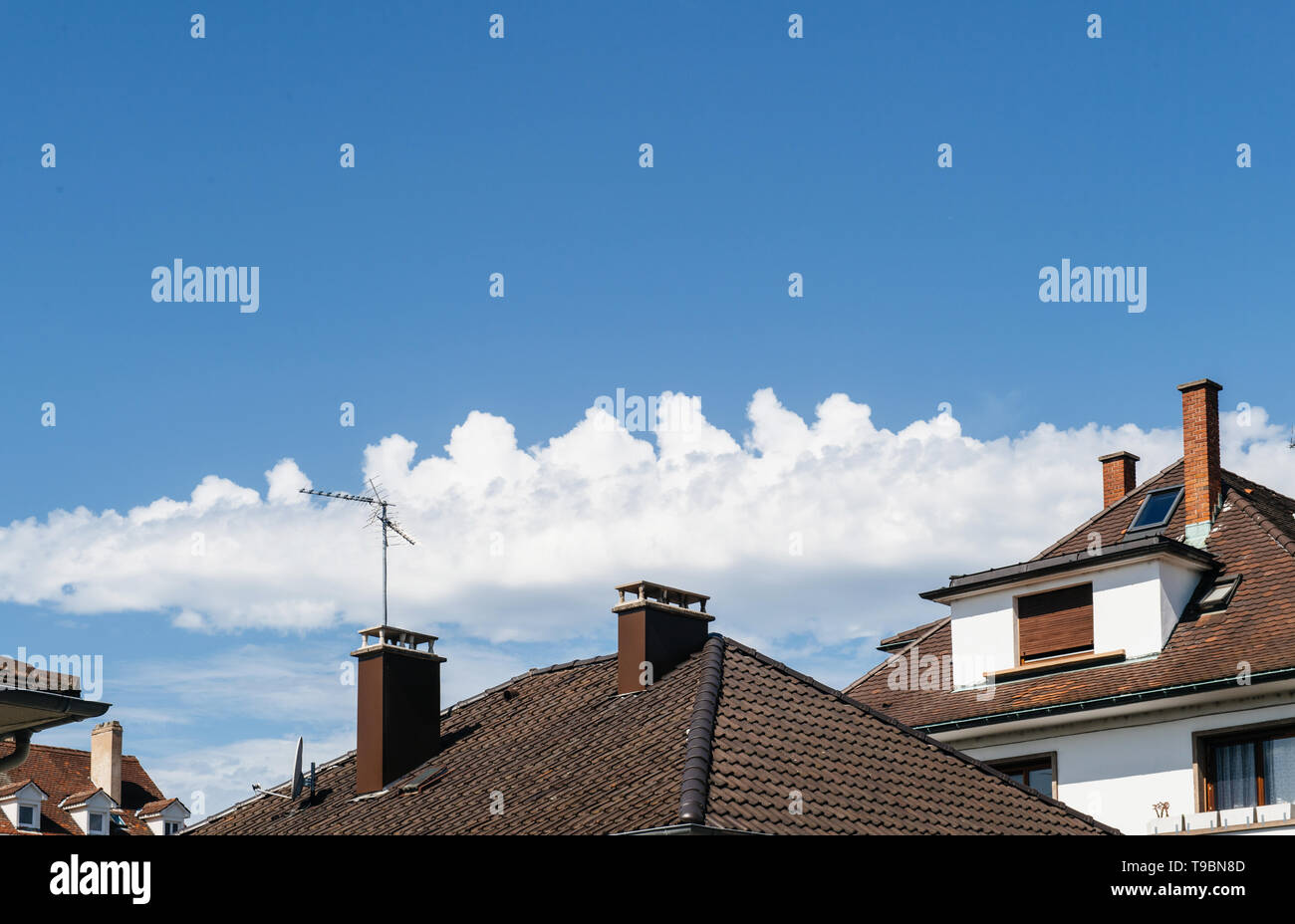 Blue sky and fluffy clouds above roofs of houses Stock Photo - Alamy
