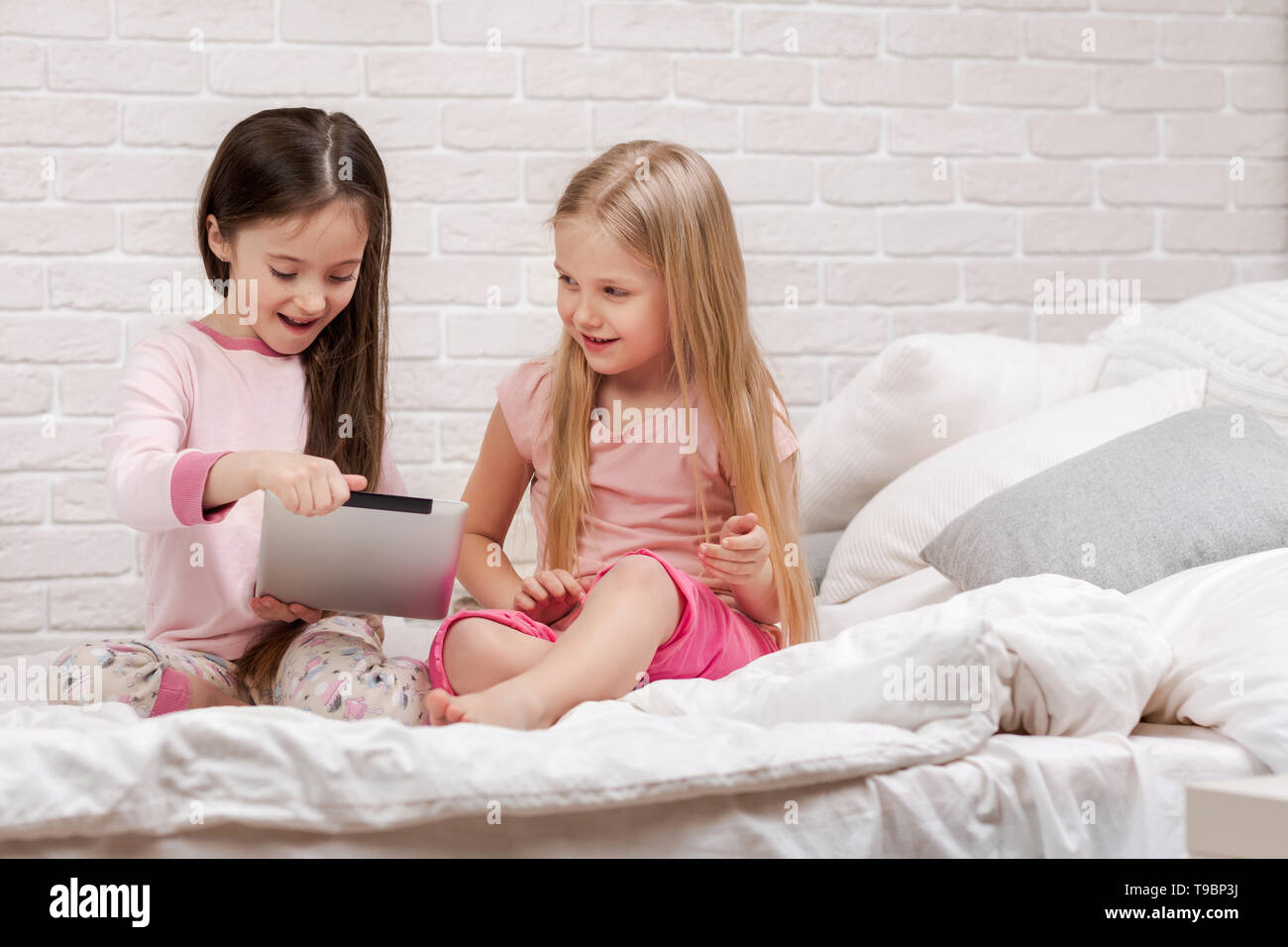 two cute children girls use digital tablet in bed. child playing on tablet pc Stock Photo Alamy