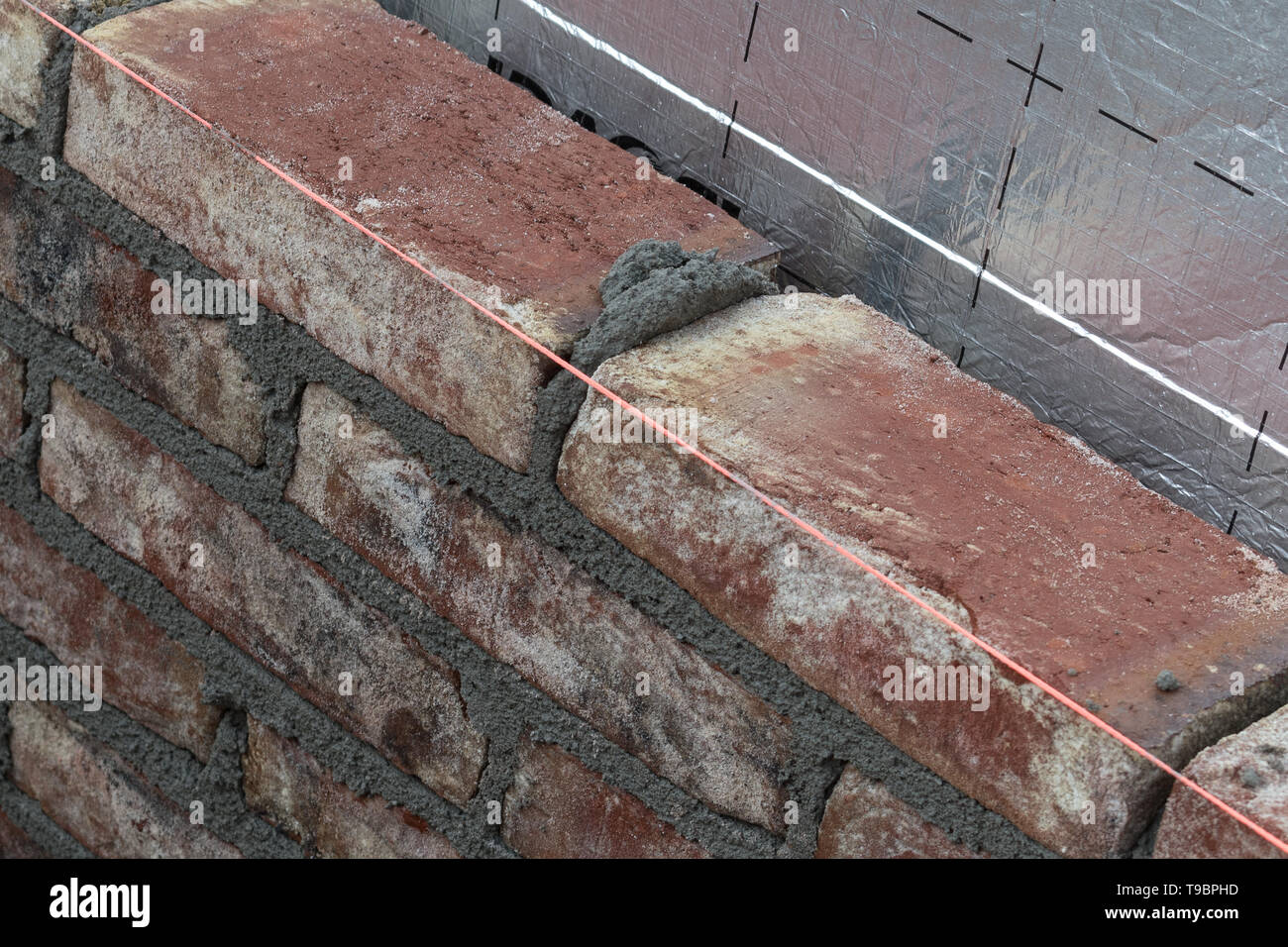 brown bricks building with silver colored isolation material behind the bricks Stock Photo