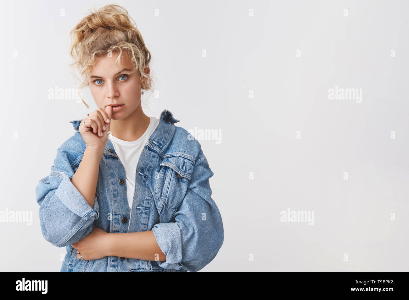 Perplexed troubled serious-looking creative smart blond curly-haired blond woman bite thumb look focused solve troublesome situation, thinking make Stock Photo