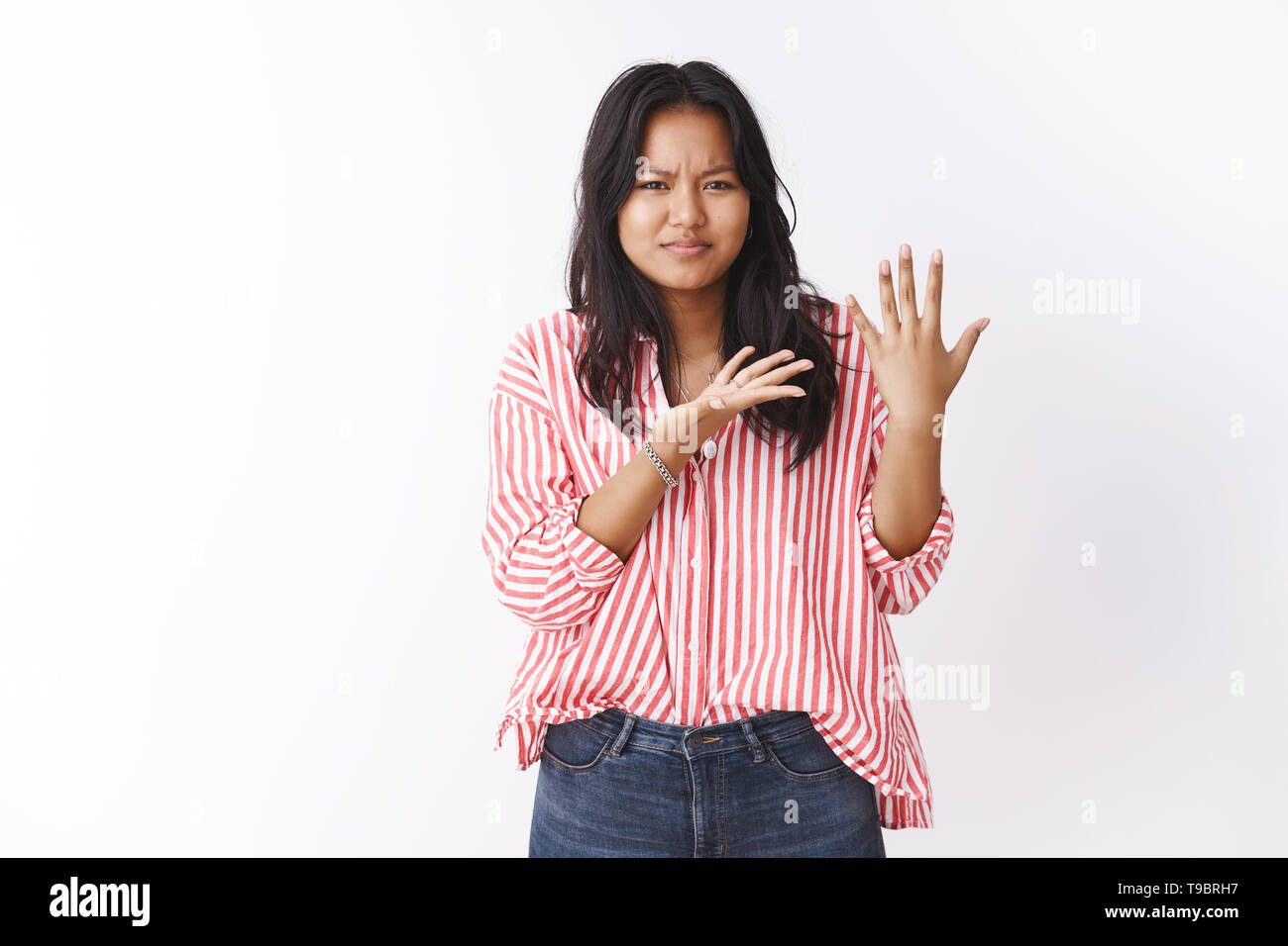 Woman feeling frustrated and displeased questioned where proposal she awaited on valentines day, showing palm without ring and pointing at arm Stock Photo