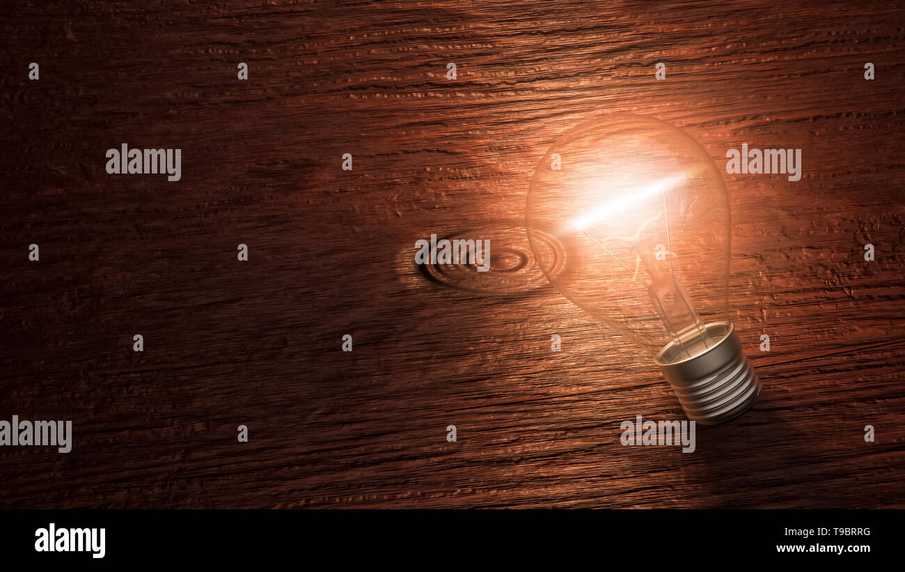 Lit up light bulb lying on a wooden background with copy space