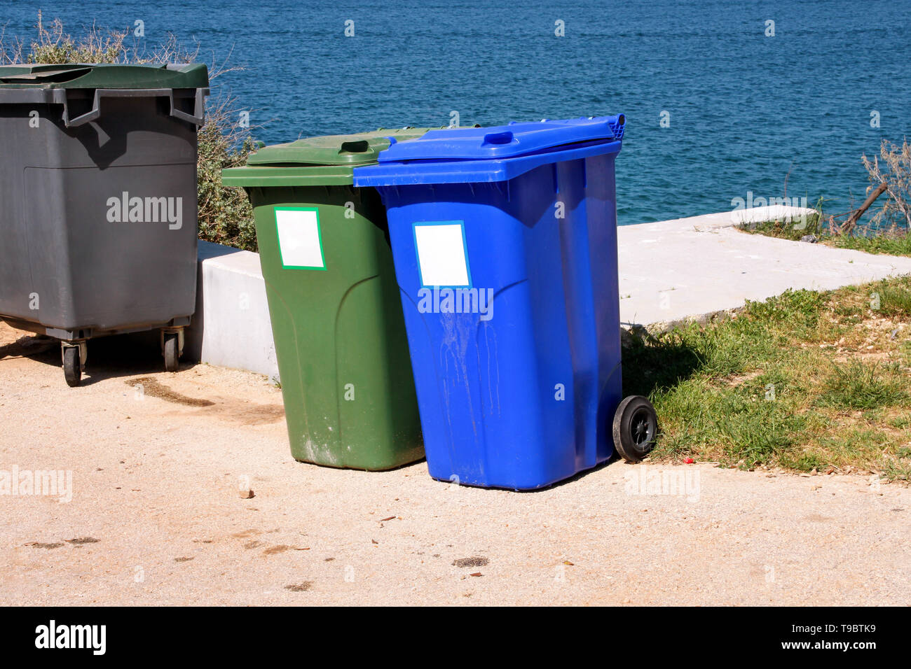 Trash can, garbage bin, recycling bin in tourist complex by sea, side of road waiting to be