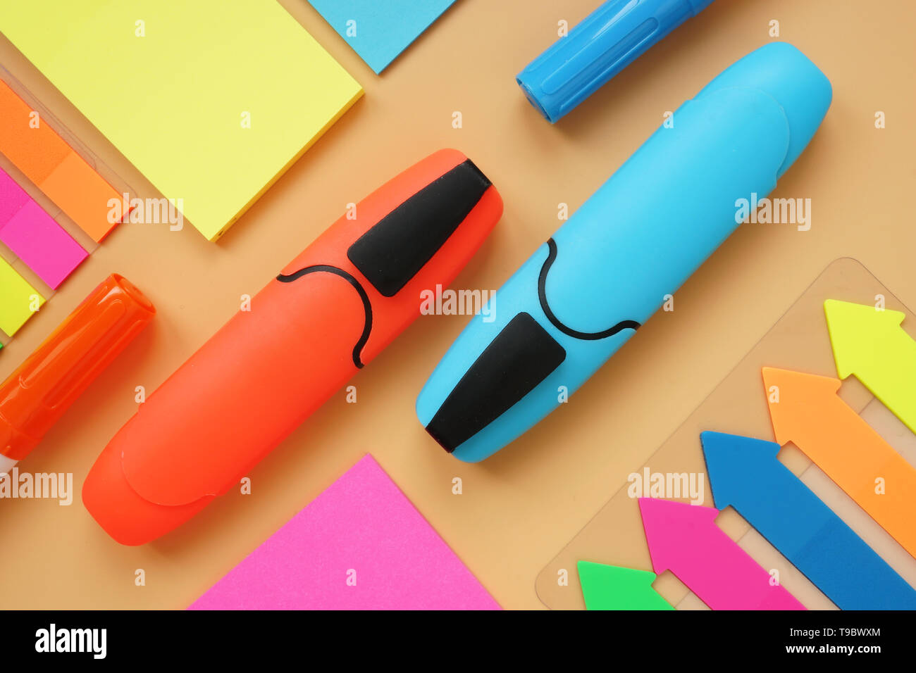 Colorful office supply on an orange surface. Top view of workspace desk. Stock Photo