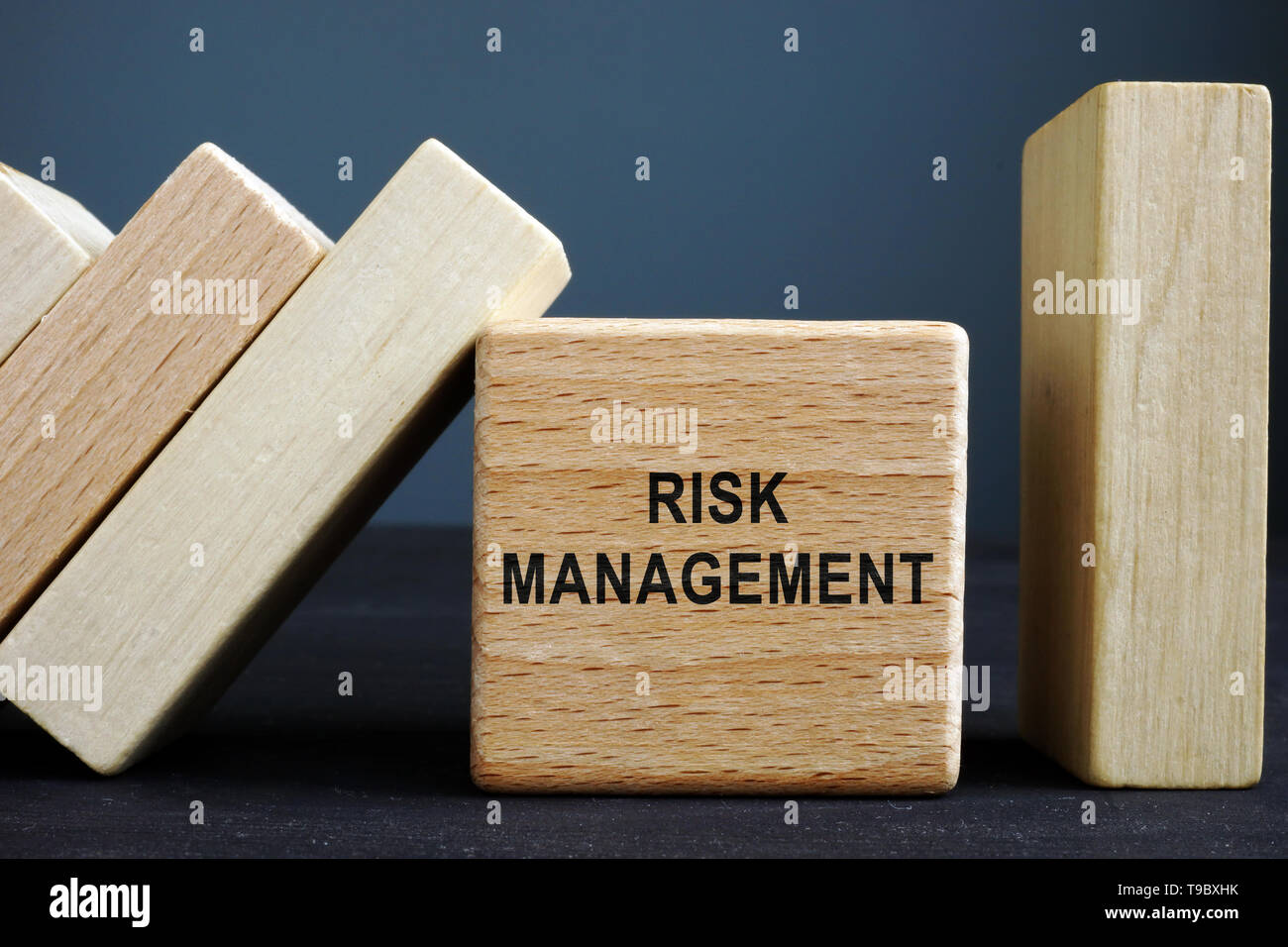 Risk management concept. Wooden cube and bricks with domino effect. Stock Photo