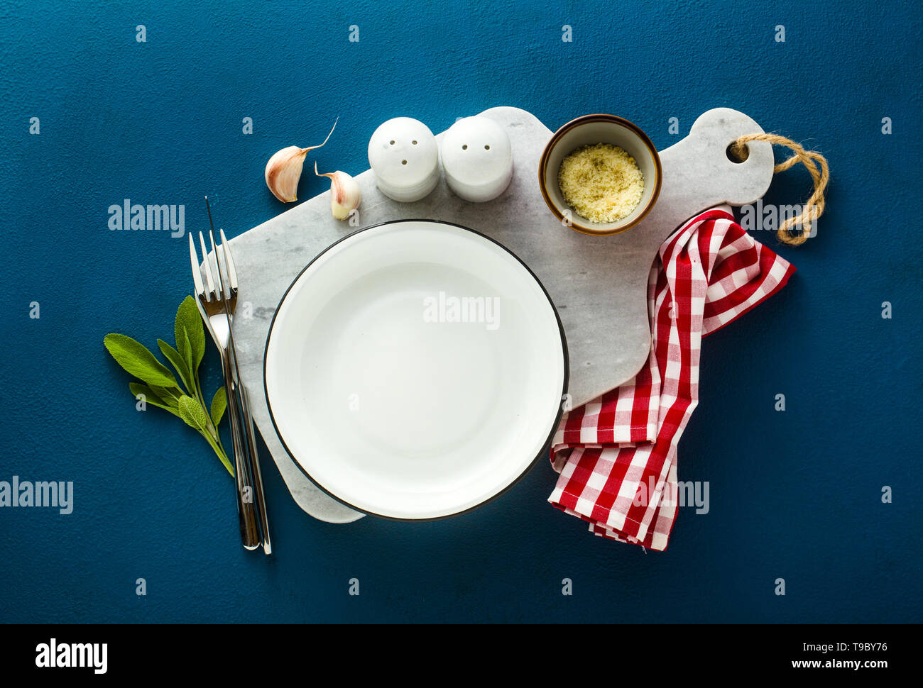 empty served plate on marble serving board and blue spice background Stock Photo
