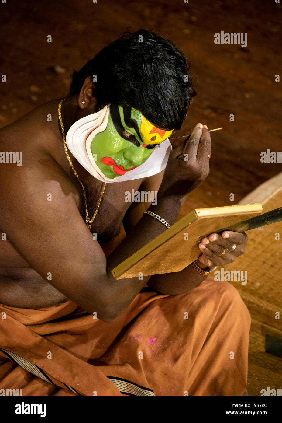 Vertical aerial view of the lead Kathakali performer putting on the distinctive green make up in Kerala, India. Stock Photo