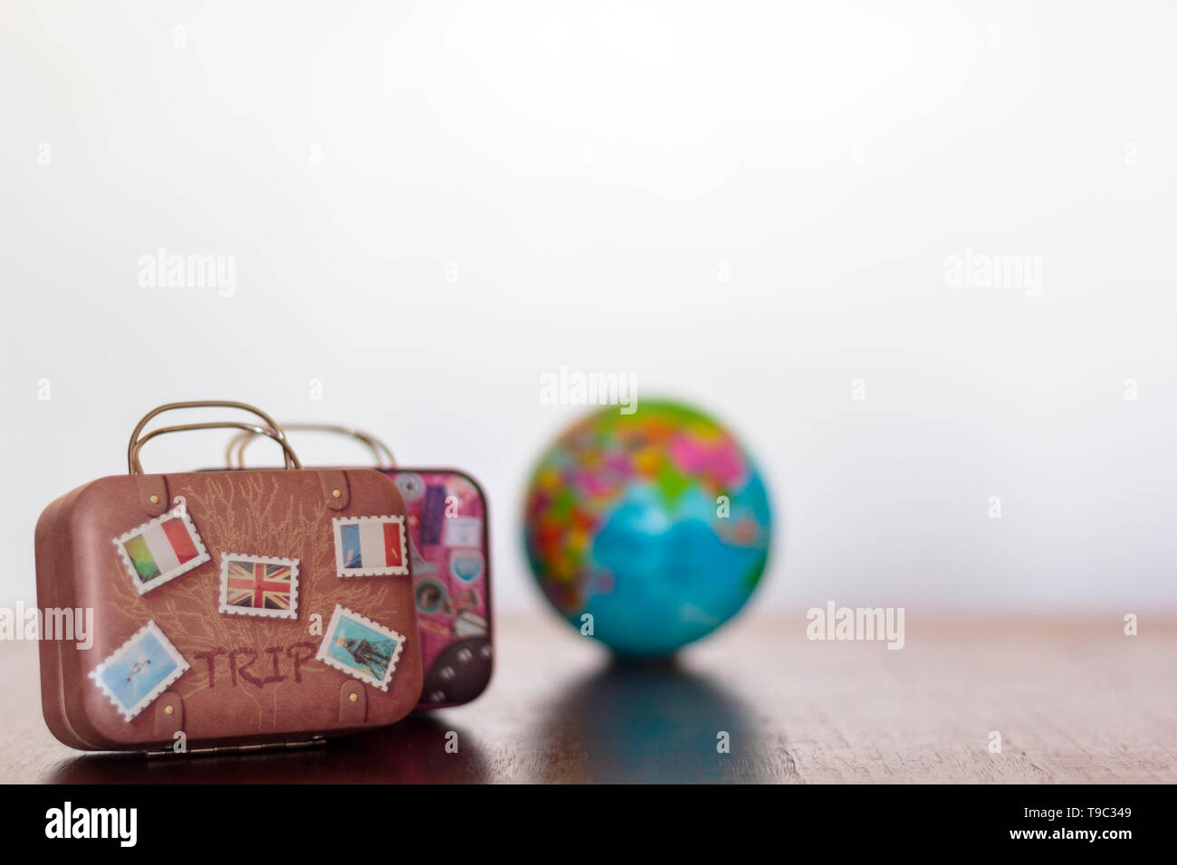 Vintage travel luggage and earth globe on a table with white background and copy space. Travel concept Stock Photo