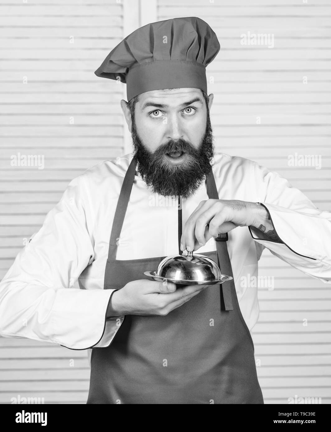Guess what i cooked. What is under lid. Delicious meal presentation. Haute  cuisine characterized meticulous preparation and careful presentation meal.  Man hat and apron hold meal covered with lid Stock Photo -