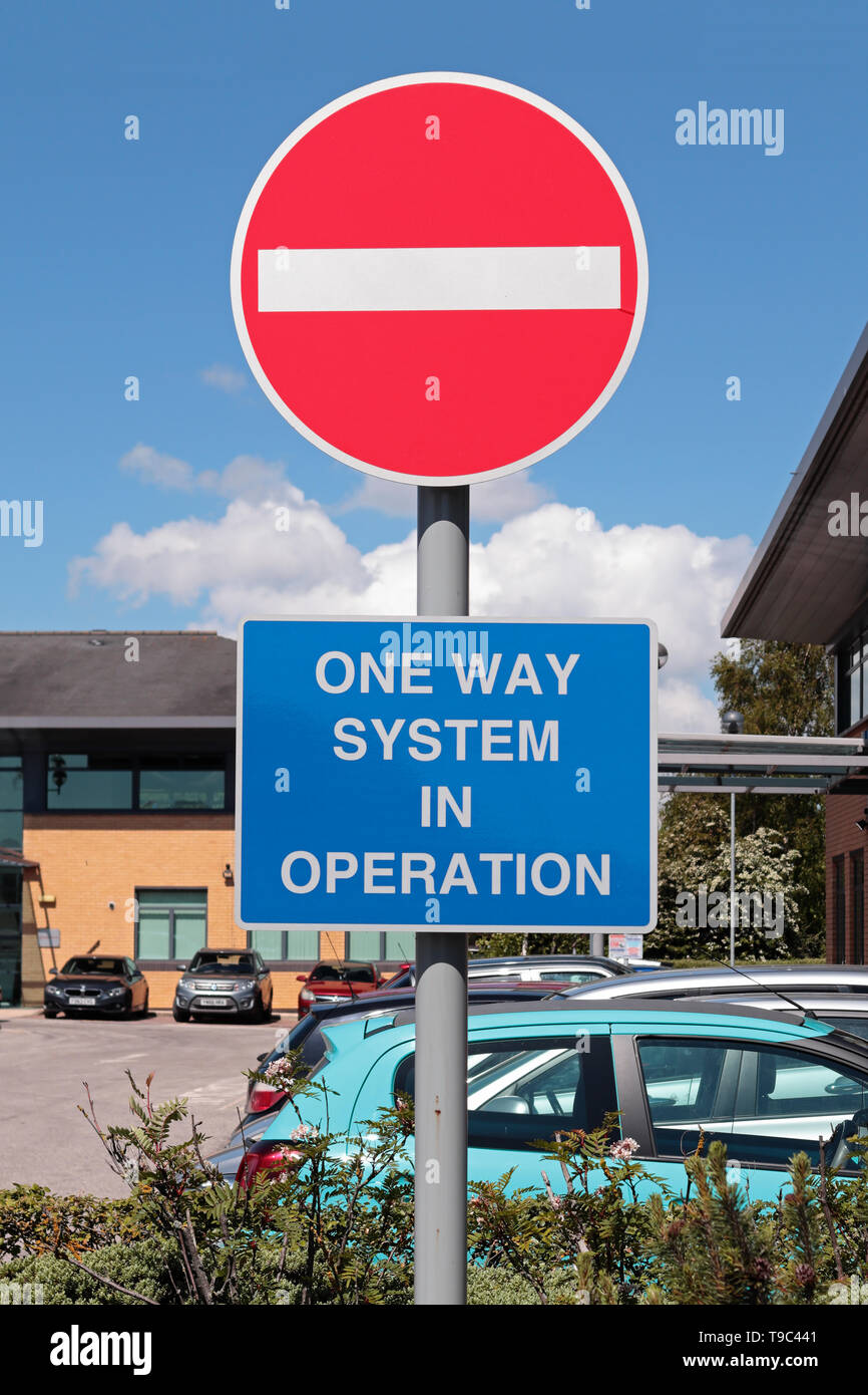 Bright Red and white 'No Entry' sign with white on blue 'One Way System in Operation' sign in an office car park Stock Photo