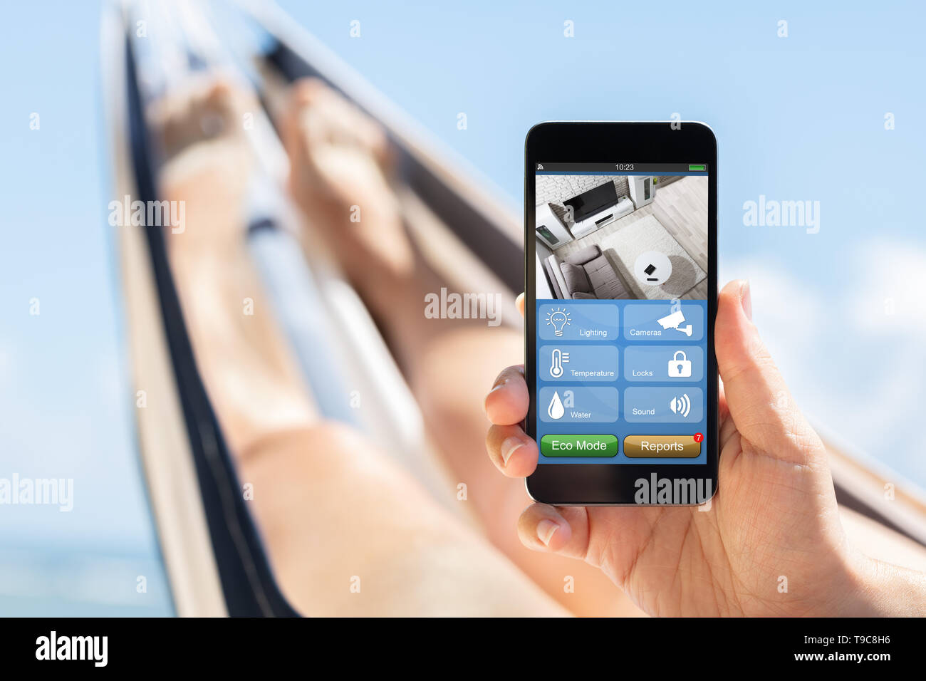 Close-up Of A Woman Lying On Hammock Holding Mobile Phone With Apps On Smart Home Stock Photo