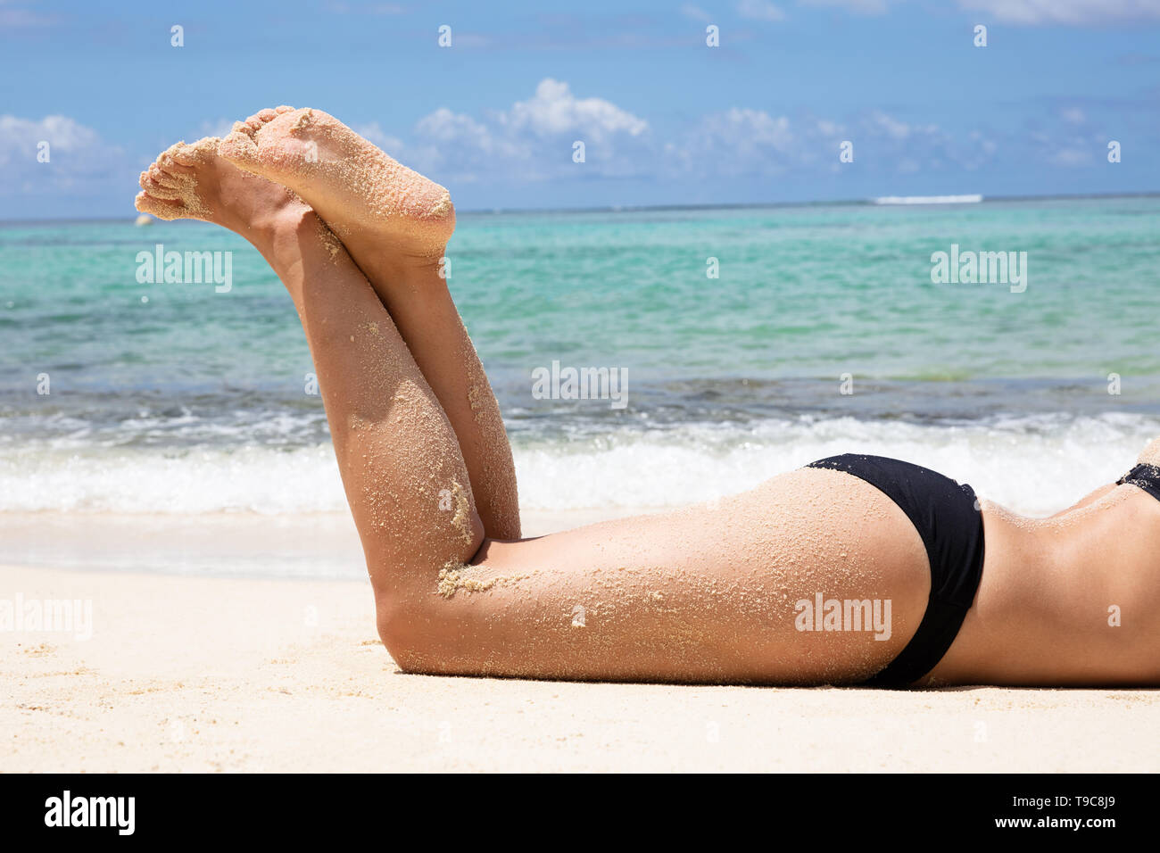 Side View Of A Young Woman In Bikini Lying On Beach Near The Sea Stock Photo