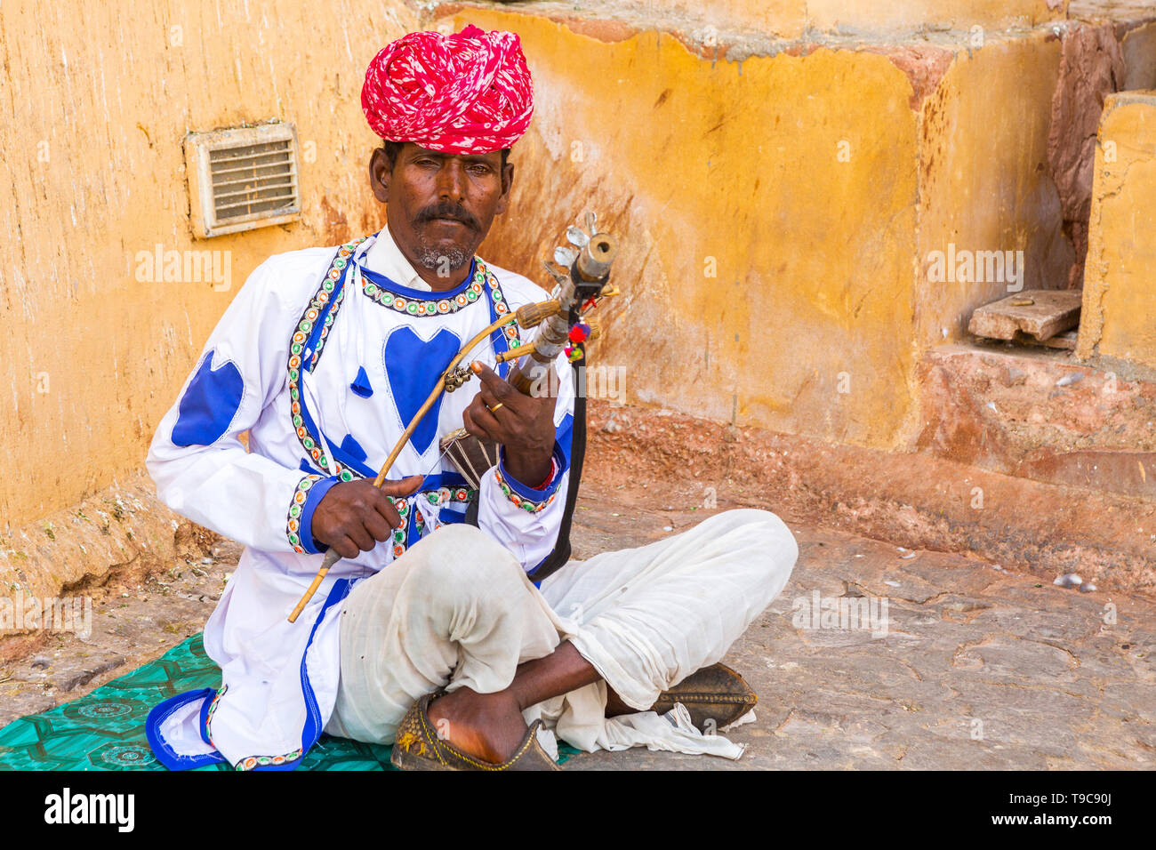 Jaipur, rajasthan, india - april 18th, 2018 : Indian village man playing traditional indian musical instrument ravanahatha at amer fort. - Image Stock Photo