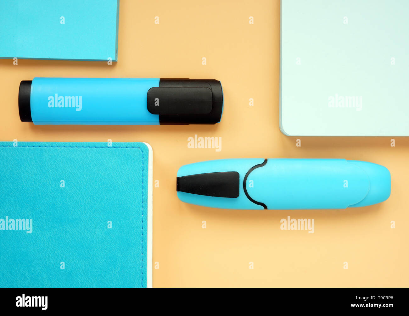 Blue notepads and markers on an orange surface. Top view flat lay of office supply. Stock Photo