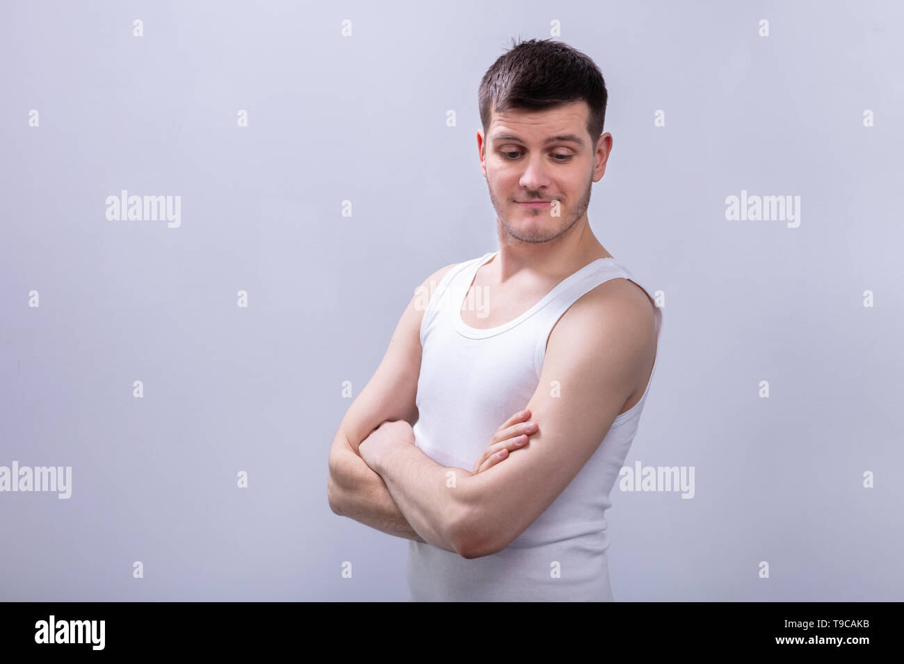 Close-up Of Happy Man In Tanktop With Folded Arms Against White Background Stock Photo
