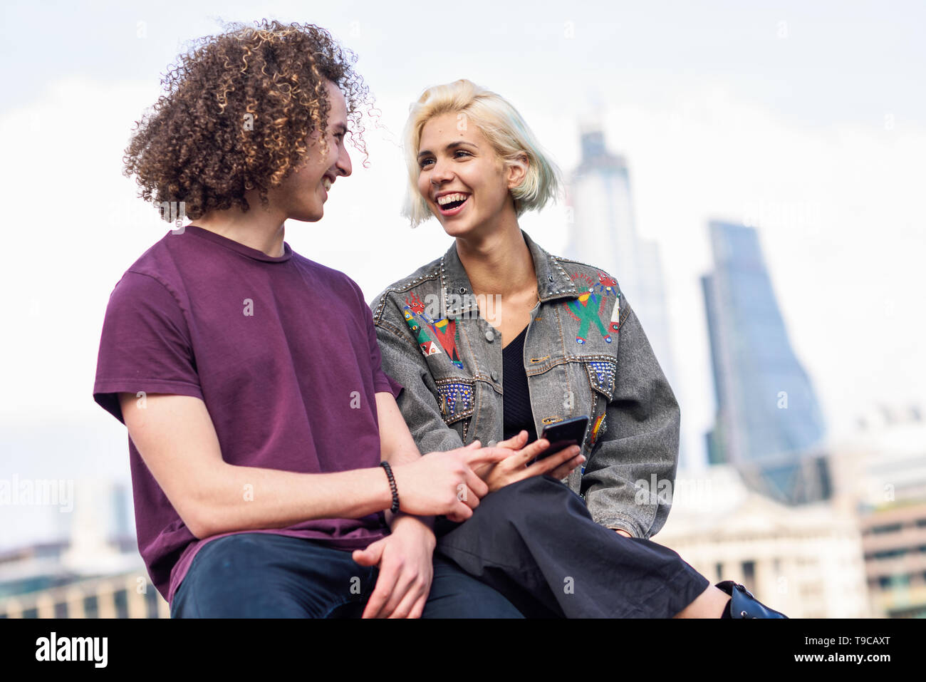 Happy couple talking sitting near River Thames. Stock Photo