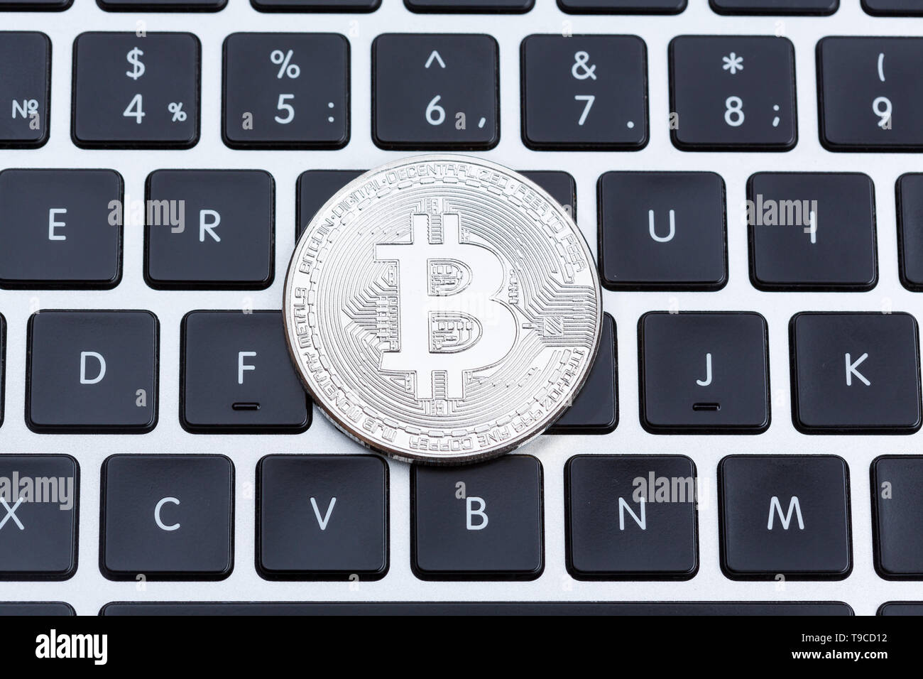 Silver bitcoin on computer key board close-up. Stock Photo