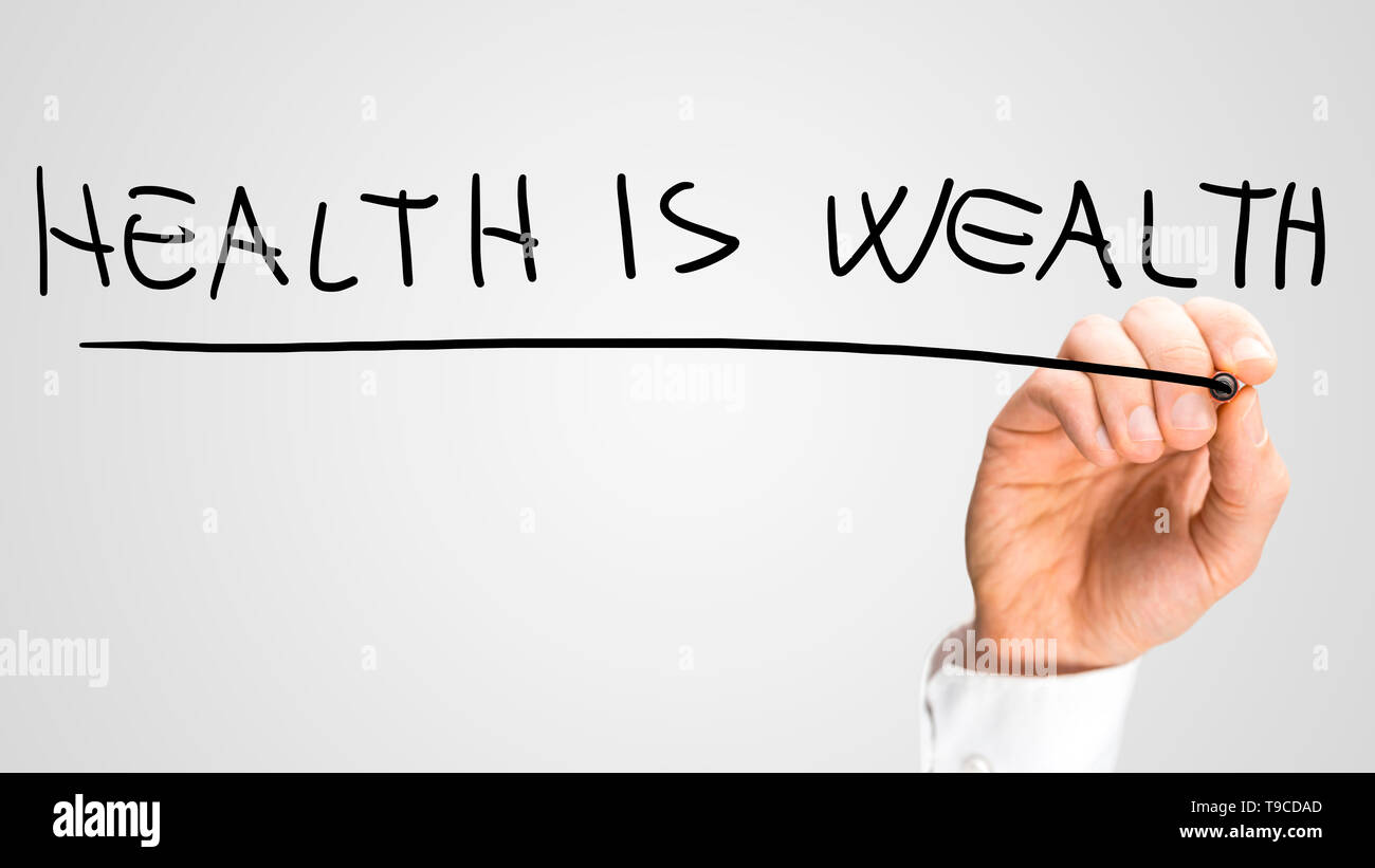 Male hand writing phrase Health is Wealth in visrtual screen. Stock Photo